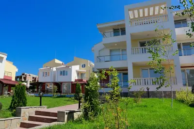 a white apartment building with a green lawn at St. Stefan Villas & Hotel in Sozopol