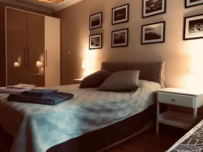 a bedroom with a bed with a nightstand and pictures on the wall at Apartament Odesos in Varna City