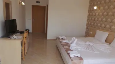 a bedroom with a bed and a desk and a television at Family Hotel Orios in Primorsko