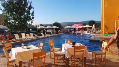 a pool with tables and chairs in front of a resort at Family Hotel Orios in Primorsko