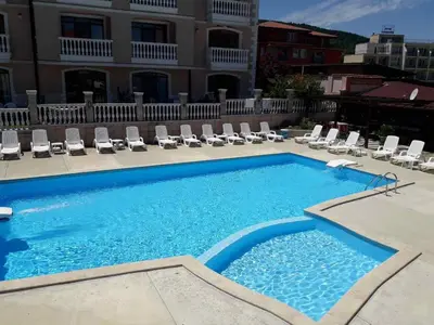 a swimming pool with lounge chairs and a building at Hotel Black Sea - Breakfast, Pool & Free Parking in Obzor