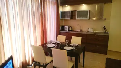 a dining room table with chairs and a kitchen at AKB Apartment Sea View in Aheloy