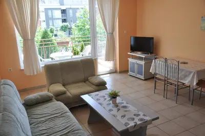 a living room with a couch and a table and a tv at Hotel BelleVille in Sunny Beach