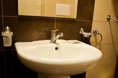 a white sink in a bathroom with a mirror at Ivanovi Apartments in Burgas City