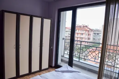 a bedroom with a bed and a large window at Ivanovi Apartments in Burgas City