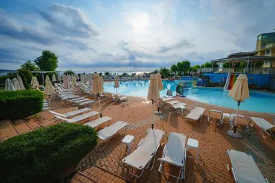 a swimming pool with lounge chairs and umbrellas at Hotel Perla Beach Club - All Inclusive in Primorsko