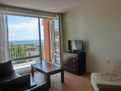 a living room with a couch and a tv and a window at Sea View Crown apartment on complex with pools and beach, Sveti Vlas in Sveti Vlas