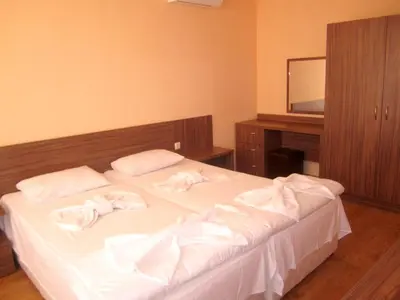 a bedroom with a bed with white sheets and a mirror at Hotel COOP Central in Obzor