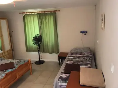 a room with two beds and a window with green curtains at Sunset House in Varna City