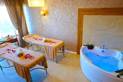 a bathroom with a tub and two tables in a room at Paradise Hotel & Relax Center in Pomorie