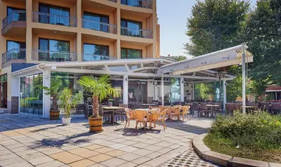 a patio with tables and chairs in front of a building at Paradise Hotel & Relax Center in Pomorie
