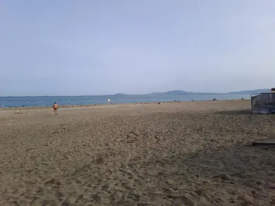 a person standing on a sandy beach near the ocean at White home-apartament in Burgas City
