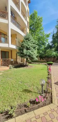 a building with a yard with pink flowers in front of it at Golden Dreams Apartment in Sunny Beach