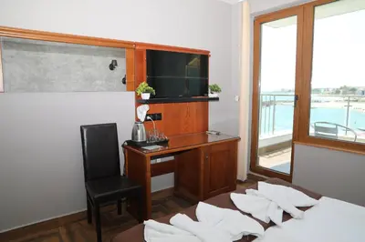 a bedroom with a desk and a bed with pillows at Petrov Family Hotel in Nesebar