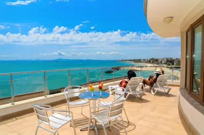 a balcony with a table and chairs and the ocean at Petrov Family Hotel in Nesebar