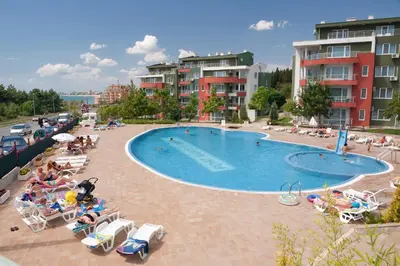 a swimming pool with chairs and people sitting around it at Green Fort Private Apartments in Sunny Beach