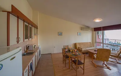 a kitchen and living room with a table and a couch at Green Fort Private Apartments in Sunny Beach