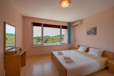 a bedroom with a bed and two windows at Green Fort Private Apartments in Sunny Beach