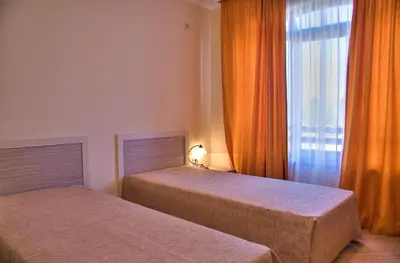 a bedroom with two beds and a window with orange curtains at Royal Sun Apartments in Sunny Beach