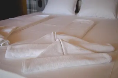 a white bed with two towels on it at Prince Cyril Hotel in Nesebar