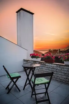 two chairs and a table on a balcony with a sunset at Prince Cyril Hotel in Nesebar