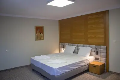 a bedroom with a white bed with a wooden headboard at Prince Cyril Hotel in Nesebar