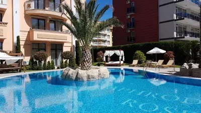 a swimming pool with a palm tree in front of a building at Aphrodite Rose Apartment in Sunny Beach