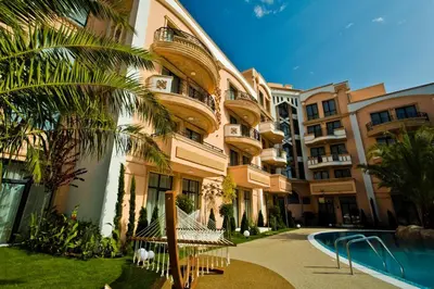 a building with a palm tree next to a swimming pool at Aphrodite Rose Apartment in Sunny Beach