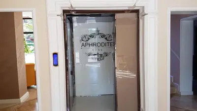 a glass elevator in a building with a sign on it at Aphrodite Rose Apartment in Sunny Beach