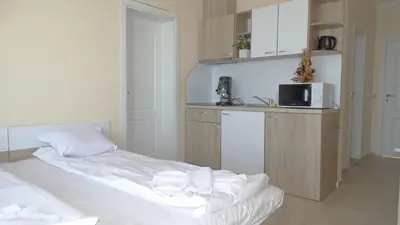a room with two beds and a kitchen with a microwave at Akrotiria Beach Apart Complex in Nesebar