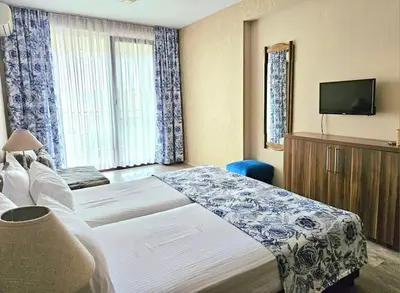 a hotel room with two beds and a flat screen tv at Villa Magnolia in Sozopol