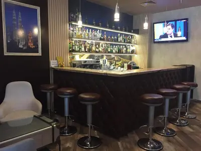 a bar with brown stools and a tv on the wall at Hotel Golden Tulip Varna in Varna City