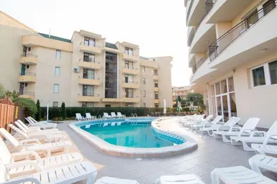 a swimming pool with white chairs and a building at Hotel Veris in Sunny Beach
