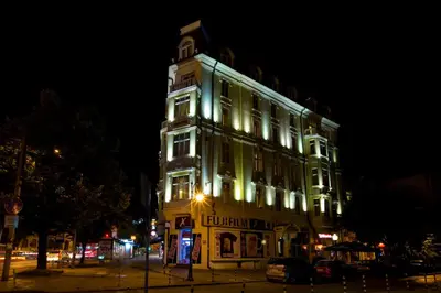 a lit up building with a clock tower at night at Boutique Splendid Hotel in Varna City