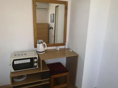 a room with a table with a microwave and a mirror at Family Hotel Verona in Sozopol