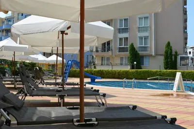 two chairs and an umbrella next to a swimming pool at Rainbow 1 Holiday Complex in Sunny Beach