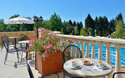 a patio with a table and chairs and a pool at Sol Nessebar Bay All Inclusive in Nesebar