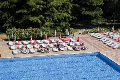 a group of people sitting in lawn chairs next to a pool at Continental Park Hotel in Sunny Beach