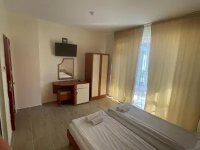 a bedroom with a bed and a desk and a window at ,,Дироси'' in Sveti Vlas