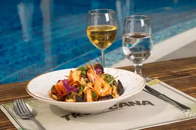 a bowl of food and a glass of wine on a table at Obzor Beach Resort in Obzor