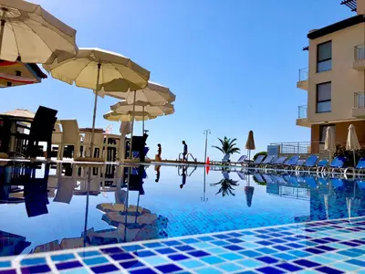 a swimming pool with umbrellas and chairs next to a building at Obzor Beach Resort in Obzor