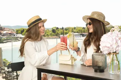 two women sitting at a table with a drink at Hotel Antea - By The Sea in Sozopol