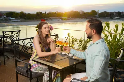 a man and a woman sitting at a table with drinks at Hotel Antea - By The Sea in Sozopol