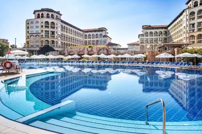 a large swimming pool with blue chairs and buildings at Melia Sunny Beach All Inclusive in Sunny Beach