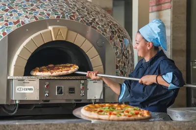a woman taking two pizzas out of an oven at Melia Sunny Beach All Inclusive in Sunny Beach