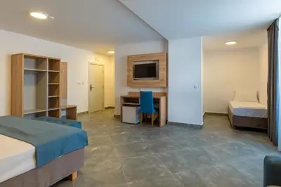 a room with two beds and a desk and a television at Martinez Hotel All Inclusive in Sozopol