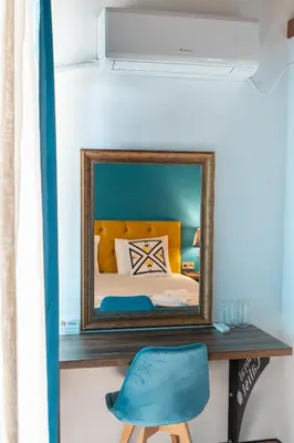 a mirror on a shelf next to a bed with a blue chair at Royal Calisto Hotel in Sozopol