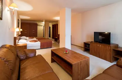a hotel room with a couch and a bed and a television at Plaza Hotel in Varna City