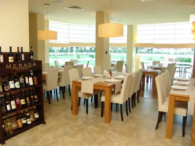 a dining room with a table and chairs and wine bottles at Aparthotel Marina Holiday Club - All Inclusive & Free Parking in Pomorie