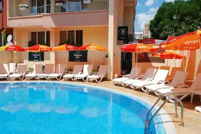 a swimming pool with chairs and umbrellas next to a hotel at Italia Hotel in Nesebar